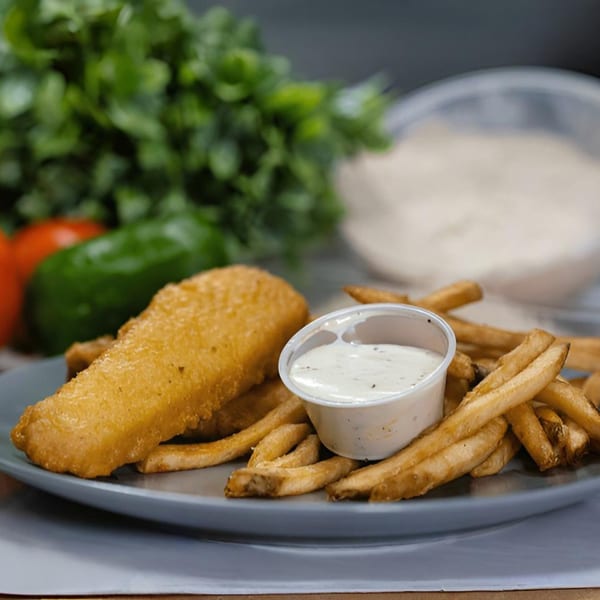 Crispy fried fish and golden french fries with a side of tartar sauce on a gray plate.